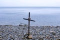 Seascape with cross of sticks on rocky beach in overcast day at sea. Royalty Free Stock Photo