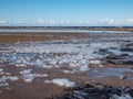 Seascape depicting landscape of Baltic sea and beach with yellow sand an frozen icce blocks in sand and blue sky in winter Royalty Free Stock Photo