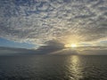 seascape with dramatic clouds and the sun setting between the sea and the cloudbase Royalty Free Stock Photo