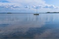 An empty boat with a mast is anchored in the sea bay on a summer day