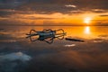 Seascape. Fisherman boat jukung. Traditional fishing boat at the beach during sunrise. Water reflection. Rising sun at horizon.