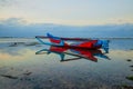 Seascape. Fisherman boat jukung. Traditional fishing boat at the beach during sunset. Cloudy sky. Water reflection. Thomas beach,