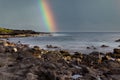 Seascape on Hawaii beach with a rainbow in the sky and ocean waves crashing onto the rocky beach Royalty Free Stock Photo