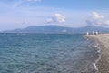 Seascape on a hot summer day, clear calm blue sea, clear sky, pebble beach, catamarans with sails and kayaks on the horizon, outdo