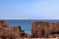 Seascape with lonely sailing yacht at sea and rocky coast of Ibiza island