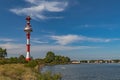 Modern navigation lighthouse on the Baltic Spit. City on the horizon of the bay. Swans and ducks swim in the water