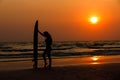 silhouettes of beautiful sexy young women surfer girls in bikinis with surfboards on a beach at sunset in sea, sport activity and Royalty Free Stock Photo