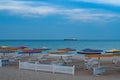 Seascape with nobody and white deck chairs stacked under colorful beach umbrellas Royalty Free Stock Photo