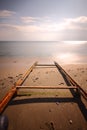 Seascape with pier and sunbeds and umbrellas and rocky shore shot with long explosure