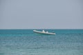 Seascape with ripple surface of blue sea water with white speedboat on anchor floating on calm waves