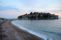 Seascape - sandy beaches of the Adriatic Sea against the backdrop of the sunset, clouds, and a group of hotels Aman Sveti Stefan,