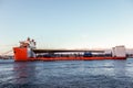 Seascape side view of a large orange semi-submersible heavy-lift ship with large load entering harbor in Stockholm Sweden.