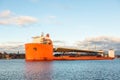 Seascape side view of a large orange semi-submersible heavy-lift ship with large load entering harbor in Stockholm Sweden.