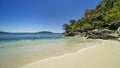 Seascape - a turquoise wave runs over the light, untouched sand of the beach, rocks of unusual shape in the coastal line