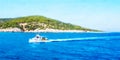 Seascape with a white boat rushing through the waves against the background of a green island