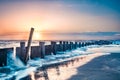 Seascape of wooden breakwater at sunrise with ocean tide