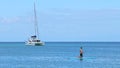 Seascape with yacht and stand up paddle boarding rower