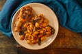 Seashell pasta in tomato and grilled chicken leg on a blue napkin.