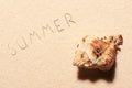 Seashell and summer lettering drawn on beach sand