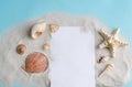 Seashells, sand and a blank sheet of paper on a blue background with space for text