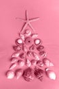 Seashells and starfish laid out as alternative Xmas tree. Trendy toning in color 2023 Viva Magenta Royalty Free Stock Photo