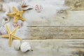 Seashells, starfish and sand on a rustic wooden background with copy space.