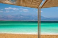 Seashore, beach with sunshades and sea and mountains in the background