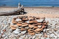 Seashore with campfire place from round pebbles and sandy beach with wooden log