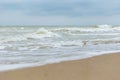 Seashore in cloudy weather. Waves with foam on the water