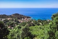 Seashore coastline with beach and rocks and rocky slope of the Island of Elba in Italy. Many people on the beach sunbathing. Blue