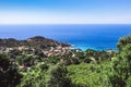 Seashore coastline with beach and rocks and rocky slope of the Island of Elba in Italy. Many people on the beach sunbathing. Blue