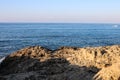 The seashore, consisting of sharp stones and centuries-old frozen lava, against the background of the sea and blue sky. Ayia Napa