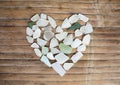 Seashore glass pebble heart on wooden background. Sugar glass mosaic for Valentine`s Day