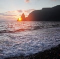 On the seashore setting sun hides behind the powerful coastal cliffs