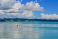 Seashores of New Zealand; beautiful seascape, bright blue ocean, and some people far away enjoying water activities.