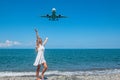Seaside Escapade: Girl in White Dress on Stones, Plane Embracing the Blue Sea Royalty Free Stock Photo