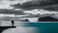 Seaside Explorer: Monochrome Scene with Man, Rucksack, Blue Sea, and Mountains. Generative AI Royalty Free Stock Photo