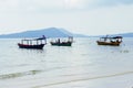 Seaside landscape with cambodian wooden boats and distant island. Idyllic seashore view with traditional khmer boats.