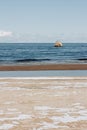 Seaside landscape in early spring day with remnants of snow in the sea sand. A washed-out shipwreck can be seen on the shore Royalty Free Stock Photo