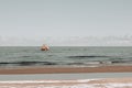 Seaside landscape in early spring day with remnants of snow in the sea sand. A washed-out shipwreck can be seen on the shore Royalty Free Stock Photo