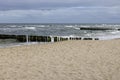 Seaside landscape, foamy water of the Baltic Sea with a wooden breakwater. Cloudy sky, Island Wolin, Miedzyzdroje, Poland