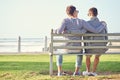 Seaside love. Rearview shot of a young gay couple sitting together on a park bench. Royalty Free Stock Photo