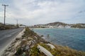 Seaside paved road along blue ocean at Korfos bay beach with white buildings, mountain and sky background Royalty Free Stock Photo