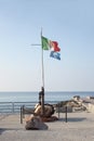 Seaside pier with Italian flag and blue flag indicating clean water condition