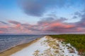 Seaside with sand dunes with snow and colorful sky at sunset, sunrise Royalty Free Stock Photo