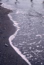 A seaside scene with waves rolling onto the beach shore with sand and small pebbles. Marine landscape with water reflections and Royalty Free Stock Photo