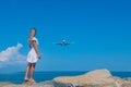 Seaside Serendipity: Girl in White Dress, Stones, Blue Sea and a Plane Royalty Free Stock Photo