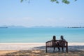 At seaside in summer , happy young couple in love relaxing on beach vacation enjoying ocean view together sitting on wooden chair Royalty Free Stock Photo