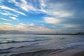 Seaside view at dusk, waves rolling on shore under a partly cloudy sky Royalty Free Stock Photo