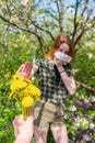 Season allergy to flowering plants pollen. Dandelion bouquet against young woman with paper handkerchief in garden and doing stop Royalty Free Stock Photo